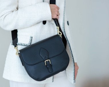 Bir mankenin elinde siyah, küçük bir kadın çantası. Modern moda bir el çantasının fotoğrafı. Günlük yaşamda şık aksesuarlar.