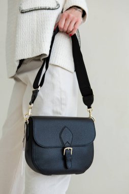 Bir mankenin elinde siyah, küçük bir kadın çantası. Modern moda bir el çantasının fotoğrafı. Günlük yaşamda şık aksesuarlar.
