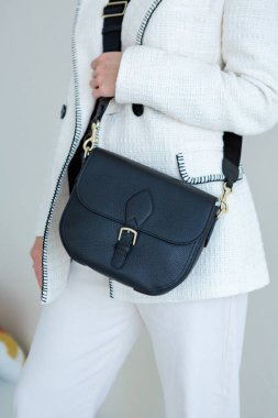 Bir mankenin elinde siyah, küçük bir kadın çantası. Modern moda bir el çantasının fotoğrafı. Günlük yaşamda şık aksesuarlar.