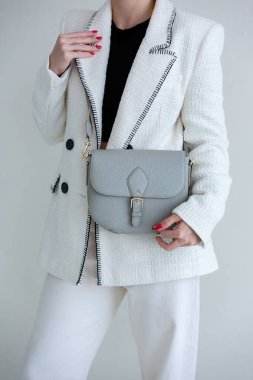 Bir modelin elinde mavi-grimsi küçük kadın çantası. Modern moda bir el çantasının fotoğrafı. Günlük hayatta şık aksesuarlar. Ayrıntılı kadın toplantıları.