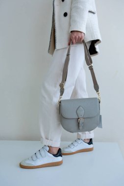 Bir modelin elinde mavi-grimsi küçük kadın çantası. Modern moda bir el çantasının fotoğrafı. Günlük hayatta şık aksesuarlar. Ayrıntılı kadın toplantıları.