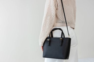 Bir mankenin elinde siyah, küçük bir kadın çantası. Modern moda bir el çantasının fotoğrafı. Günlük yaşamda şık aksesuarlar.