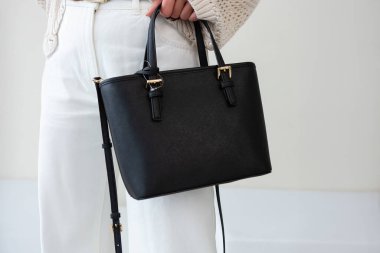 Bir mankenin elinde siyah, küçük bir kadın çantası. Modern moda bir el çantasının fotoğrafı. Günlük yaşamda şık aksesuarlar.