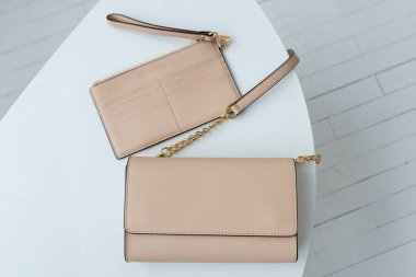 Altın zincir kayışlı bej deriden bir çapraz-beden çantası, minimalist tasarım, beyaz bir masaya yerleştirilmiş. en üstteki görünüm