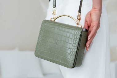 Yeşil dokular, altın mobilyalı deri çapraz vücut çantası, minimalist tasarım, bir model üzerinde..