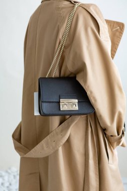 Bir modelin üzerinde siyah küçük bir kadın çantası. Modern moda bir el çantasının fotoğrafı. Günlük hayatta şık aksesuarlar. Ayrıntılı kadın toplantıları.