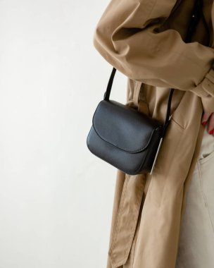 Bir modelin üzerinde siyah küçük bir kadın çantası. Modern moda bir el çantasının fotoğrafı. Günlük hayatta şık aksesuarlar. Ayrıntılı kadın toplantıları.