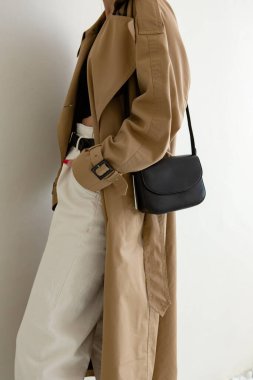 Bir modelin üzerinde siyah küçük bir kadın çantası. Modern moda bir el çantasının fotoğrafı. Günlük hayatta şık aksesuarlar. Ayrıntılı kadın toplantıları.