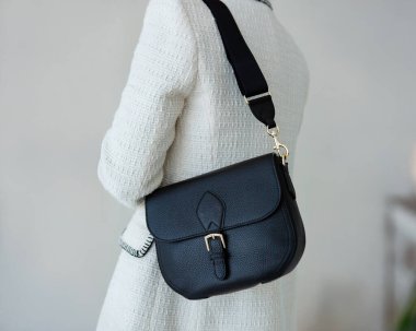 Bir mankenin elinde siyah, küçük bir kadın çantası. Modern moda bir el çantasının fotoğrafı. Günlük yaşamda şık aksesuarlar.