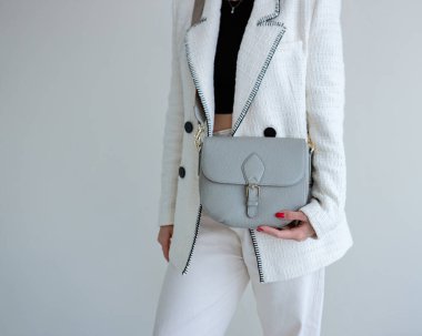 Bir modelin elinde mavi-grimsi küçük kadın çantası. Modern moda bir el çantasının fotoğrafı. Günlük hayatta şık aksesuarlar. Ayrıntılı kadın toplantıları.