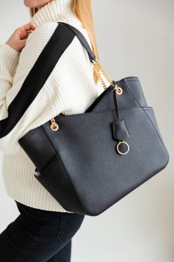 Bir mankenin elinde siyah, küçük bir kadın çantası. Modern moda bir el çantasının fotoğrafı. Günlük yaşamda şık aksesuarlar.