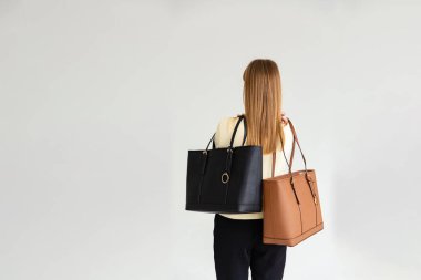 Bir mankenin elinde iki küçük kadın çantası. Modern moda bir el çantasının fotoğrafı. Ayrıntılı kadın toplantıları.