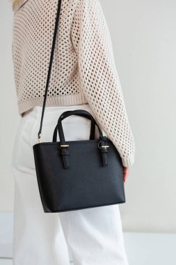 Bir mankenin elinde siyah, küçük bir kadın çantası. Modern moda bir el çantasının fotoğrafı. Günlük yaşamda şık aksesuarlar.