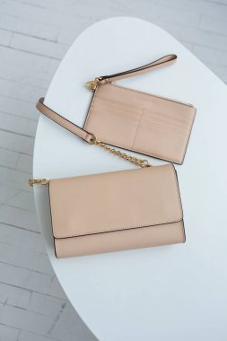 Altın zincir kayışlı bej deriden bir çapraz-beden çantası, minimalist tasarım, beyaz bir masaya yerleştirilmiş. en üstteki görünüm