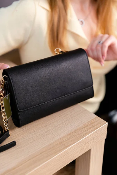 Bir mankenin elinde siyah, küçük bir kadın çantası. Modern moda bir el çantasının fotoğrafı. Günlük yaşamda şık aksesuarlar.