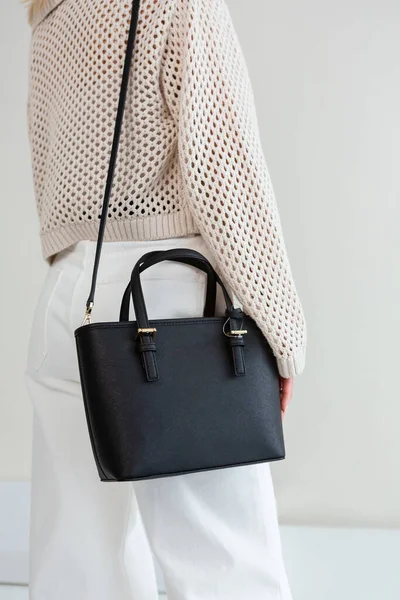 Bir mankenin elinde siyah, küçük bir kadın çantası. Modern moda bir el çantasının fotoğrafı. Günlük yaşamda şık aksesuarlar.