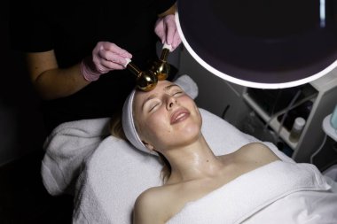 Farklı sıcaklıklarda ağır altın bir aletle yüz masajı