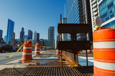 İnşaat ekipmanları şehrin bir yerine kurulmuş. Yakınlarda, çalışma alanını gösteren turuncu bariyerler var. Açık bir gökyüzüne karşı çevresindeki yüksek binalar.