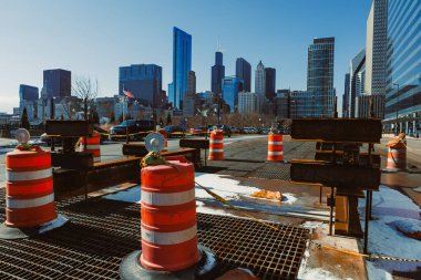 İnşaat bariyerleri şehrin ufuk çizgisinin önüne kurulur. Açık mavi gökyüzünün altında binalar yükseliyor. Kar yerde, kışın geldiğini gösteriyor..