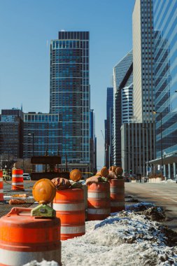 Trafik konileri şehir ortamında devam eden inşaata işaret ediyor. Açık mavi gökyüzünün altındaki yüksek binalar bölgeyi çevreledi. Kıştan beri yerde kar var..