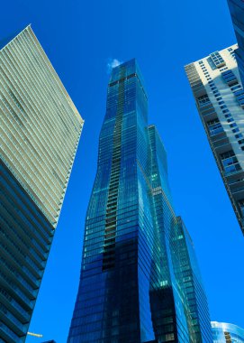 Gökyüzüne doğru uzanan camdan yapılmış modern uzun binalar Skyline 'da yer alıyor. Gündüzleri şehir içi olarak kullanılıyor. Güneş ışığı cam yüzeylerden yansıyor..