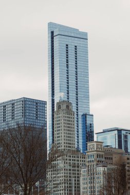 Şehir silueti, kentsel alanda bulutlu bir gökyüzünün altında yan yana duran modern ve tarihi binaları gösteriyor.