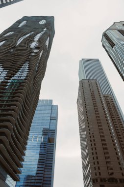 Şehir merkezinde bulutlu bir günde insanlar cam ve betondan yapılmış yüksek binaların altında yürürler..