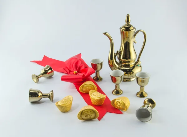 Lingote de oro lazo rojo jarra de oro vaso de té sobre fondo blanco — Foto de Stock