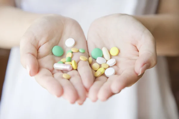 Mulher está segurando um monte de comprimidos diferentes — Fotografia de Stock
