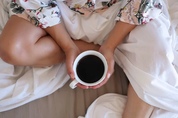 Close up of young woman with cup of coffee in bed at home — Stock Photo, Image