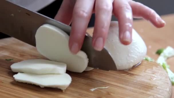 Vrouwelijke handen snijden mozzarella kaas op de houten snijplank — Stockvideo