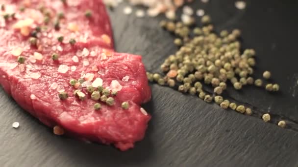 Filete de carne de res cruda con pimienta de maíz y tomillo y diferentes especias en botellas de vidrio listo para asar a la parrilla en madera tabla envejecida figura sobre la mesa 1920x1080 movimiento de introducción escondite lento hd — Vídeo de stock