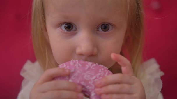 Niña comiendo donut rojo, rosado, donut, macro, cerca — Vídeo de stock