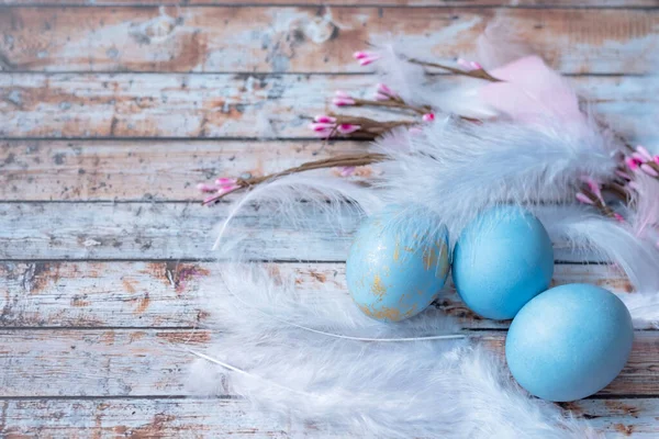 Blue easter eggs with feathers on wooden background. Minimal easter concept. Easter card with copy space for text