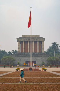 Hanoi 'deki Ho Chi Minh Mausoleum' un dışındaki Ba Dinh Meydanı 'nda puslu ve kötü kirlenmiş bir günde bir bahçıvan yürüyor. Şehir 14. Vietnam Komünist Partisi Kongresi için 19-25 Ocak 2026 tarihleri arasında dekore edildi..