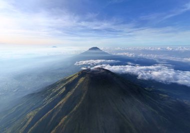 Bulut denizini delip geçen bir dağ silsilesinin çarpıcı hava görüntüsü. Huzurlu, ilham verici ve görkemli. Seyahat, doğa ve macera temalı projeler için ideal
