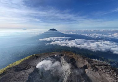 Bulutların üzerindeki volkanın çarpıcı hava görüntüsüne tanık olun. Doğanın ihtişamını tecrübe et. Seyahat, macera ve çevresel temalar için ideal. Hayranlık ve merak uyandırır