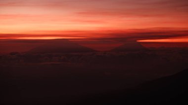 Bulutlarla kaplı dağ tepelerinde dramatik bir gün doğumu. Ateşli kırmızı ve turuncu gökyüzü korku ve macera hissi yaratır. Seyahat, doğa ya da motivasyon teması için mükemmel. Manzara Görünümü