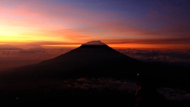 Nefes kesici bir gün doğumuna karşı hazırlanmış çarpıcı bir dağ siluetine tanık olun. Canlı renkler gökyüzünü boyuyor, barış ve merak sahnesi yaratıyor. Seyahat, doğa ve ilham için ideal.