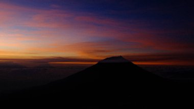 Renkli bir alacakaranlık gökyüzüne karşı dramatik bir dağ silueti. Macera, seyahat, manzara ve doğa kavramlarını yakalayın. Geçmiş, turizm ve macera görselleri için ideal