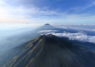 Bulut denizini delip geçen bir dağ silsilesinin çarpıcı hava görüntüsü. Huzurlu, ilham verici ve görkemli. Seyahat, doğa ve macera temalı projeler için ideal