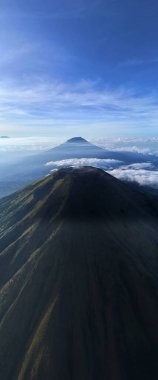 Nefes kesen dağ manzarası. Zirveler bulutların üzerinde yükselir. Doğa, seyahat, macera ve çevre temaları için idealdir. Huzuru, barışı ve büyük ölçekleri çağrıştırıyor