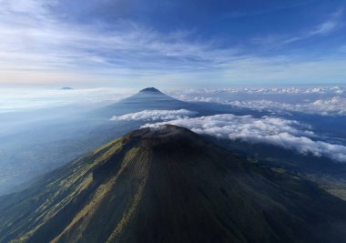 Endonezya 'da yükselen bir bulut denizi üzerinde yükselen volkanik dağların ihtişamını yakala. Seyahat, doğa, macera ve manzara yayınları için ideal. Huşu ve gezinti arzusu uyandırır.