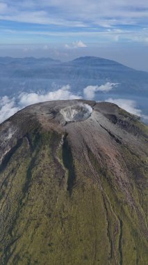 Nefes kesici hava manzarası görünür krateri olan görkemli bir volkan sergiliyor. Yeşil yamaçlar ve bulutlu gökyüzü sakin ama güçlü bir manzara yaratır. Macera ve jeoloji temaları için ideal