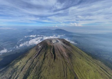Yükselen bir volkanın bulunduğu hava manzarasının zirvesi yumuşak bulutlarla dolu bir gökyüzüne doğru uzanıyor. Huzur ve macerayı çağrıştırıyor. Seyahat, doğa ve coğrafya temaları için mükemmel
