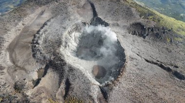 Hava görüntüsü volkanın kraterini ortaya çıkarıyor, buhar güçlü bir şekilde yükseliyor. Eğitim, seyahat, çevre keşfi veya araştırma potansiyeli sunan doğal bir mucize.