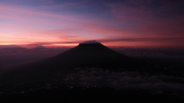 Canlı bir gündoğumuna karşı dramatik bir dağ silueti. Gökyüzü pembe, mor ve turuncu renklerle parlıyor. Seyahat, doğa ya da ilham verici konular için ideal