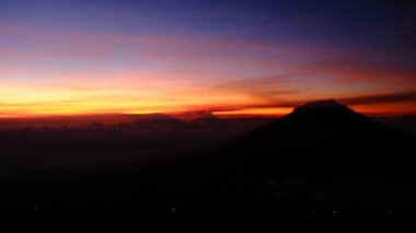 Bu manzarayla şafağın dinginliğini yakala. Canlı gökyüzünün altında bir dağ silueti görüyorum. Seyahat, doğa ve barış temaları için ideal. Korku, macera ve merak uyandırır.