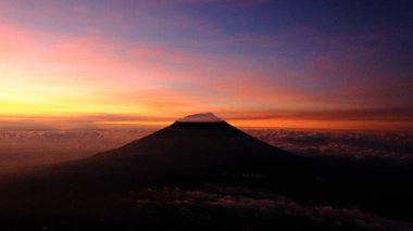 Gündoğumu gökyüzünü turuncu, pembe ve mor renklerle boyar, bir dağ zirvesi silueti gibi. Macera, sükunet ve doğal güzellik ilham verir. Seyahat için mükemmel, doğa temaları