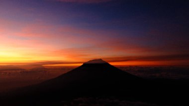 Kızgın gündoğumu gökyüzüne karşı bir dağ tepesi silueti yakala. Hayranlık uyandıran doğa görüşü merak ve sükunete ilham verir. Seyahat, macera ya da manzara görselleri için mükemmel